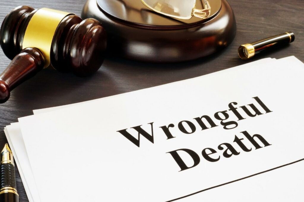 The words wrongful death written on a piece of white paper beside a gavel and an uncapped fountain pen.