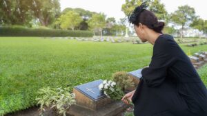 A young woman placing white roses on a loved one’s memorial marker; wrongful death and non-economic damages concept.