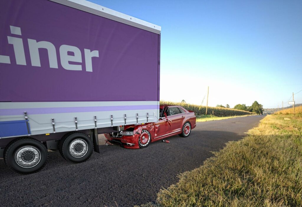 Image of auto being dragged under semi-truck; trucking accident.