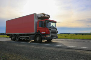 A commercial truck traveling a country highway at dawn; avoiding trucking accidents.