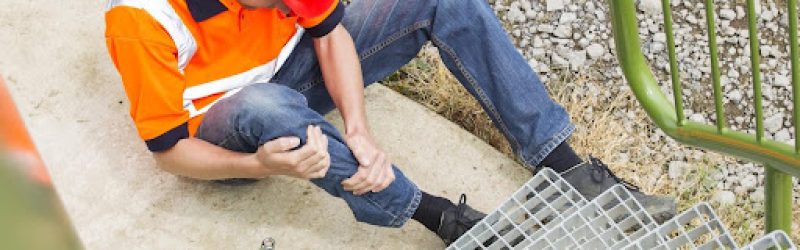 A construction worker holding his leg in pain at the base of some steps, wondering what damages are recoverable under workers’ compensation.