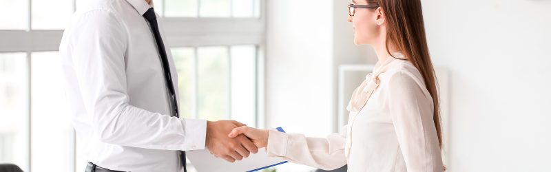 A personal injury lawyer greeting a client with a handshake in an office setting.