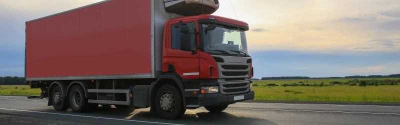 A commercial truck traveling a country highway at dawn; avoiding trucking accidents.