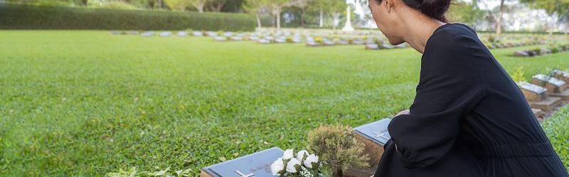 A young woman placing white roses on a loved one’s memorial marker; wrongful death and non-economic damages concept.